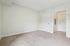 Princeton Westford Apartments | A clean, empty room in an apartment in Westford MA, featuring beige carpet, off-white walls, two closed white doors, and a small entryway. The space is well-lit with natural light and offers a simple, modern appearance. | Apartments with Washer & Dryer in Westford
