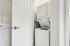 Princeton Westford Apartments | A compact laundry area in an apartment in Westford, MA, featuring a stacked in-home washer/dryer behind a partially open white door; the washer lid is open, and the space is enclosed by light-colored walls. | Apartments with Washer & Dryer in Westford