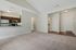 Princeton Westford Apartments | Bright, empty apartment in Westford MA featuring a spacious living room with beige carpet, adjacent to an open kitchen with stainless steel appliances and dark cabinets; entryway with white doors and wood flooring visible. | Pet Friendly Apartments in Westford