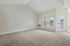 Princeton Westford Apartments | A spacious, empty apartment in Westford MA with beige carpet, light-colored walls, a large window, and a glass door leading outside. The vaulted ceiling and abundant natural light create an inviting atmosphere. | Apartments with Washer & Dryer in Westford