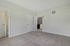 Princeton Westford Apartments | A clean, empty primary bedroom with light beige walls, two white doors, and freshly vacuumed carpet. One door opens to a hallway while the other leads to an ensuite bathroom. There is a small vent on the wall. | One bedroom apartments in westford
