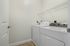 Princeton Westford Apartments | A laundry room in an apartment in Westford MA features a white in-home washer/dryer side by side, a wire shelf above, and beige tile flooring against plain white walls. | Two bedroom apartments in westford
