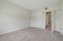 Princeton Westford Apartments | Empty room in an apartment in Westford MA with light beige walls and carpet flooring, featuring two white doors (one slightly open), white baseboards, and a vent above the doors. The space is well-lit by natural light. | Apartments with EV Charging in Westford