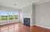Grandview Apartments | Bright, empty room with large windows overlooking greenery at Grandview Apartments in Lowell MA, hardwood floors, light gray walls, and a white gas fireplace with a black hearth. | Pet Friendly Apartments in Lowell