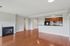 Grandview Apartments | Spacious living area at Grandview Apartments in Lowell, MA, featuring hardwood floors, a cozy fireplace on the left, and an open kitchen with dark wood cabinets and black appliances. Light gray walls with white trim add a modern touch. | Apartments with Balcony in Lowell