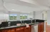 Grandview Apartments | Modern kitchen with dark granite countertops, wooden cabinets, and stainless steel appliances at Grandview Apartments in Lowell MA, open to a bright living area with large windows, a fireplace, and views of greenery outside. | Apartments with Washer & Dryer in Lowell