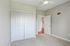 Grandview Apartments | A bright, empty room at Grandview Apartments in Lowell MA features beige carpet, light gray walls, a ceiling fan, white double closet doors, and an open door leading to a hallway with wood flooring. | Lowell Waterfront Apartments