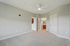 Grandview Apartments | Empty bedroom with light gray walls, beige carpet, a white ceiling fan, and three doors—one to a bathroom, another to a closet, and a third open to a hallway in Grandview Apartments in Lowell MA. | Apartments with Washer & Dryer in Lowell