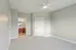 Grandview Apartments | A bright, empty bedroom at Grandview Apartments in Lowell, MA features light gray walls, white trim, gray carpet, a ceiling fan, two closed doors, and an open doorway to a bathroom with double sink vanity and large mirror. | Wheelchair Accessible Apartments in Lowell