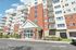 Grandview Apartments | Grandview Apartments Lowell MA is a modern multi-story building with white siding and red brick exterior, featuring balconies, large windows, and a main entrance with a covered porch and landscaped flower beds. | Pet Friendly Apartments in Lowell