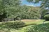 Grandview Apartments | A small pond surrounded by grassy slopes and trees, some with green and others turning red, sits near Grandview Apartments in Lowell, MA. A chain-link fence stands in the background under a blue sky with scattered clouds. | Pet Friendly Apartments in Lowell