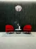 Two red armchairs on a gray rug with a round white table and a white vase with flowers between them, set against a dark textured wall and a modern ceiling light&mdash;an inviting space | The Charley | Apartment in Allston, MA