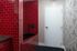 Modern Pet Spa in Allston MA with glossy red subway tiles around a black bathtub, a white door with a silver handle, and black-and-white patterned wallpaper. The dark-tiled floor lends the space a chic vibe&mdash;perfect for an at-home pet spa. | The Charley | Apartment in Allston, MA