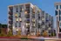 Modern multi-story apartment building with illuminated windows at dusk, featuring balconies and a geometric facade. Some greenery is visible in the foreground of The Charley Apartments in Allston MA, with light trails from passing vehicles on the street. | The Charley | Apartment in Allston, MA