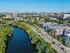 Aerial view of a city with a river beside a busy road, bordered by green trees and modern buildings like The Charley Apartments in Allston, MA, all under a clear blue sky. | The Charley | Apartment in Allston, MA