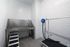 A clean, white-tiled Pet Spa room at The James Apartments in Haverhill MA features a stainless-steel washing station, black ramp, grooming table, and an air-drying hose&mdash;perfectly designed for pet grooming and bathing. | The James | Apartment in Haverhill, MA