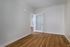 Bright, empty room at The James Apartments in Haverhill MA featuring light beige walls, wood flooring, and a white framed glass door slightly open to another space with matching floors. Natural light fills the inviting area.  | The James | Apartment in, Haverhill MA