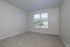 Empty room at The James Apartments in Haverhill, MA featuring beige carpet, light walls, and a large window with white blinds allowing natural light in. Enjoy views of trees and greenery just outside your window.  | The James | Apartment in, Haverhill MA