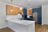 Modern kitchen at The James Apartments in Haverhill, MA, featuring a white island, stainless steel appliances, blue lower cabinets, wood uppers, a marble backsplash, and stylish pendant lights over the countertop.  | The James | Apartment in, Haverhill MA