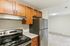Princeton Place Apartments | A kitchen at Princeton Place Apartments in Worcester MA features stainless steel appliances, including an electric stove and refrigerator, wooden cabinets, and a light marble countertop. An adjacent empty, carpeted living area is partially visible. | Worcester Apartments with Virtual Tours