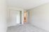 Princeton Place Apartments | Empty bedroom with light beige walls, an open white door, a closet with sliding doors, and light gray carpet flooring at Princeton Place Apartments in Worcester, MA. The room is well lit with natural light. | Apartments with Balcony in Worcester
