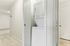 Princeton Place Apartments | A stacked white washer and dryer set is neatly placed inside a small laundry closet with an open door in the carpeted hallway at Princeton Place Apartments in Worcester MA. | Apartments with Washer & Dryer in Worcester