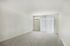 Princeton Place Apartments | Spacious empty room at Princeton Place Apartments in Worcester MA features white walls, beige carpet, a wall-mounted air conditioning unit, and large sliding glass doors with vertical blinds that let in natural light. | Apartments with Balcony in Worcester