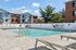 Princeton Place Apartments | A clean outdoor swimming pool at Princeton Place Apartments in Worcester MA is surrounded by a paved deck with lounge chairs, a white privacy fence, and apartment buildings in the background under a partly cloudy sky. | Apartments with Balcony in Worcester