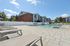 Princeton Place Apartments | Outdoor swimming pool area with lounge chairs, surrounded by a white fence, in front of the three-story Princeton Place Apartments in Worcester, MA, on a sunny day with a clear blue sky. | Apartments with Air Conditioning in Worcester