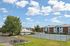 Princeton Place Apartments | A sunny outdoor scene at Princeton Place Apartments in Worcester MA, featuring tennis courts surrounded by a chain-link fence, apartment buildings in the background, a few trees, a picnic table, and a bike rack with several bicycles nearby. | Worcester Apartments with Pickleball Court
