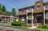 Charming brick apartment building with private balconies and lush green surroundings, perfect for serene living.