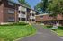 Charming brick apartment complex with balconies, lush greenery, and a welcoming walkway.