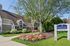 Pheasant Run Apartments | A modern clubhouse with large windows and a brown roof stands behind a swimming pool surrounded by lounge chairs at Pheasant Run Apartments in Nashua, NH, all beneath a clear blue sky. | Apartments with Balcony in Nashua