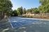 Pheasant Run Apartments | A clean outdoor swimming pool at Pheasant Run Apartments in Nashua NH is surrounded by lounge chairs, potted plants, and a white fence, with trees and a building in the background on a sunny day. | Apartments with Balcony in Nashua