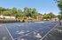 Pheasant Run Apartments | Outdoor swimming pool surrounded by blue lounge chairs, white fence, and potted plants at Pheasant Run Apartments, with brick apartment buildings and tall green trees in Nashua NH on a sunny day. | Apartments with Air Conditioning in Nashua