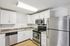 Princeton Properties | A modern kitchen at Brookstone Manor Apartments in Milford, New Hampshire features white cabinets, stainless steel appliances including a refrigerator, oven, microwave, dishwasher, a double sink, and wood flooring. | Milford Apartments with Virtual Tours
