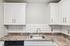 Princeton Properties | Experience a modern kitchen at Brookstone Manor Apartments in Milford, New Hampshire, featuring white cabinets, a stainless steel sink, marbled countertop, subway tile backsplash, and a built-in dishwasher below the counter. | Pet Friendly Apartments in Milford