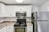 Princeton Properties | Modern kitchen at Brookstone Manor Apartments in Milford, New Hampshire, featuring white cabinets, a stainless steel refrigerator, a built-in microwave, an electric stove with black burners, brown marble countertops, and a white tile backsplash. | Apartments with Washer & Dryer in Milford