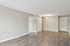 Princeton Properties | A spacious, empty room at Brookstone Manor Apartments in Milford, New Hampshire, featuring light gray walls, white trim, wood-style flooring, two white doors, a ceiling light fixture, and a white entry door in the background. | Pet Friendly Apartments in Milford
