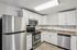 Princeton Properties | Modern kitchen at Brookstone Manor Apartments in Milford, New Hampshire, with white cabinets, stainless steel appliances, marble-look countertops, subway tile backsplash, and light wood flooring. | Apartments with Washer & Dryer in Milford