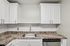 Princeton Properties | A modern kitchen at Brookstone Manor Apartments in Milford, New Hampshire features white cabinets, a stainless steel sink with a gooseneck faucet, a tiled backsplash, speckled brown countertops, and a built-in dishwasher beneath the counter. | Milford Apartments with Virtual Tours