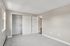 Princeton Properties | A clean, empty bedroom at Brookstone Manor Apartments in Milford, New Hampshire features light beige walls, two windows, a white closet door, and soft gray carpet. There are electrical outlets on the wall for your convenience. | Apartments with Air Conditioning in Milford