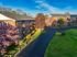 Charming brick apartment complex surrounded by lush greenery and blooming trees, featuring spacious balconies and a serene atmosphere.