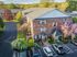 Charming brick apartment building surrounded by lush greenery and blooming trees, featuring well-maintained gardens and convenient parking spaces.