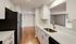 Modern kitchen with sleek white cabinets and countertops, stainless steel appliances, and elegant hardwood floors opening to a bright living area.Your spacious kitchen offers generous square footage with room for multiple people and all your cooking essentials.  | The Royal Crest | Apartment in,North Andover MA
