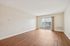 Bright and spacious living area with elegant wooden flooring, featuring large glass doors opening to a scenic balcony view.| Village Green | Apartment in Tewksbury, MA