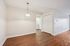 Inviting room with elegant hanging light fixture, polished hardwood floors, and ample closet space leading to a modern kitchen area.| Village Green | Apartment in Tewksbury, MA