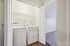 Modern in-unit laundry area with washer and dryer neatly tucked behind white double doors, featuring a sleek, minimalist design.| Village Green | Apartment in Tewksbury, MA