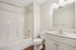 Elegant bathroom with a sleek white bathtub, modern vanity, and ample lighting, offering a serene oasis.| Village Green | Apartment in Tewksbury, MA