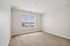 Bright, spacious bedroom with plush carpet and large window offering a charming neighborhood view.| Village Green | Apartment in Tewksbury, MA